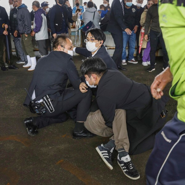 A man, on the ground, who threw what appeared to be a smoke bomb, is caught at a port in Wakayama, western Japan Saturday, April 15, 2023. Japan’s NHK television reported Saturday that a loud explosion occurred at the western Japanese port during Prime Minister Fumio Kishida’s visit, but there were no injuries. (Kyodo News via AP)